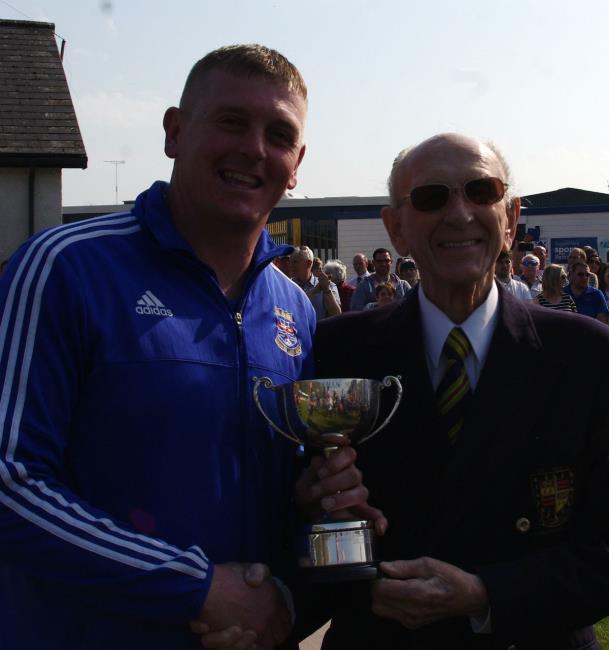 Winning manager Kristan Bennett receives Llillian Holman Memorial Cup from Royston Holman